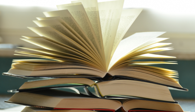 Open faced book with groundwood paper surrounded by more books of varying paper-types